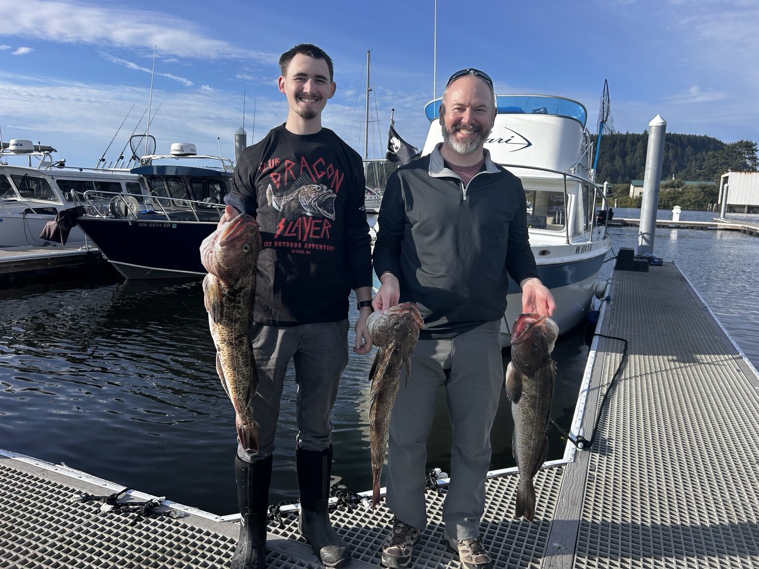 Two KYS Outdoor Adventures guests displaying lingcod beside the F/V Safari